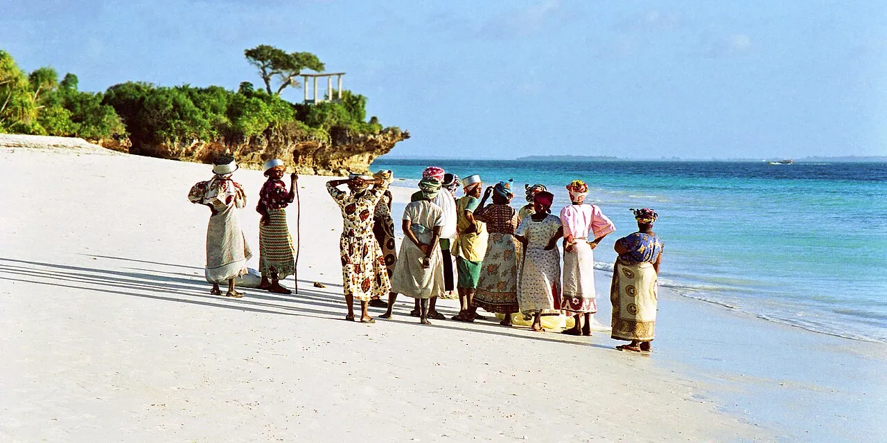 Women in colourful clothes walking along a Zanzibar beach
